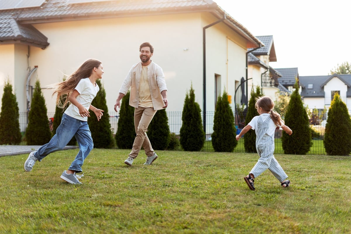 Father and daughters joyfully running and playing together in the garden on a sunny afternoon