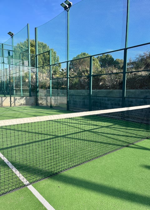 Cancha de pádel con piso sintético verde y cielo despejado