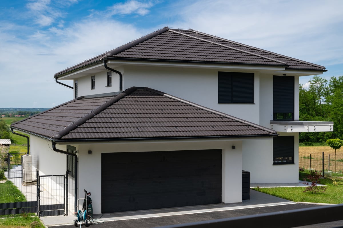 White two-story modular modern house with a large dark garage door, minimalist design
