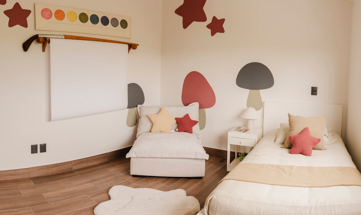 Modern childrens bedroom with two twin beds, whimsical mushroom and star wall decals, whiteboard, wooden flooring, and colorful decorative elements