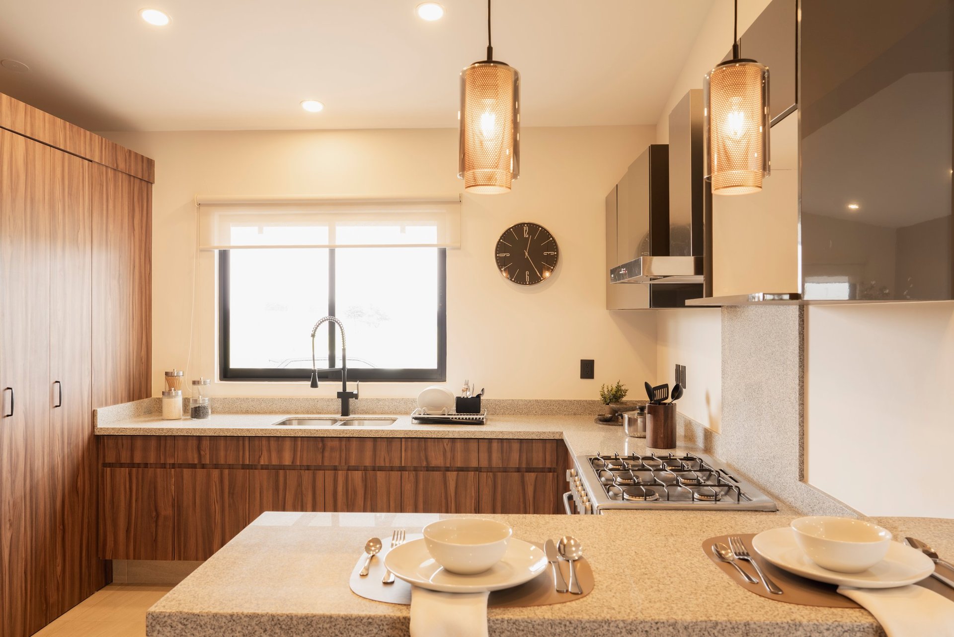 Modern kitchen with wood cabinetry, island with place settings, pendant lighting, and stainless steel appliances