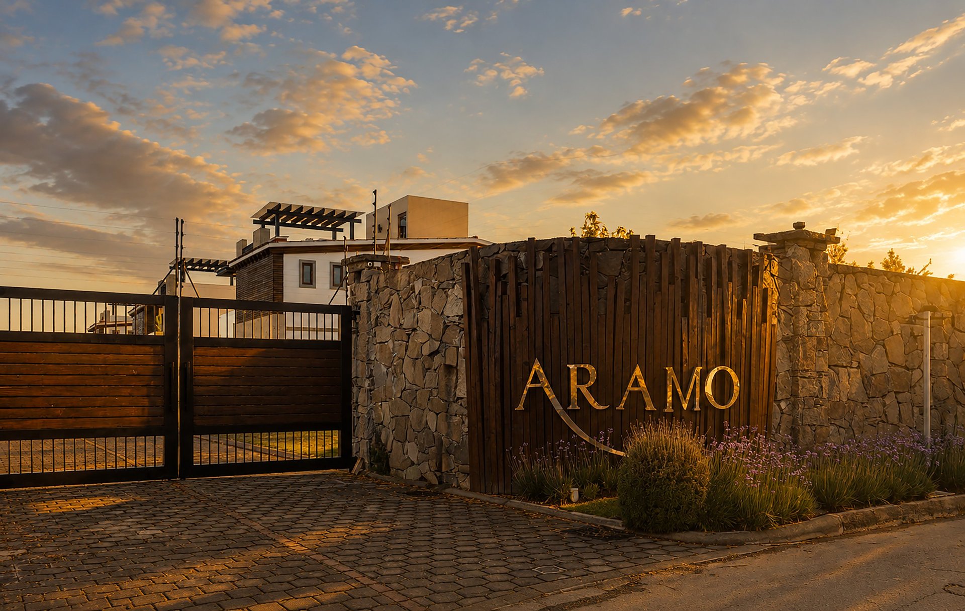 Aramo entrance with stone wall and metal gate at sunset, architectural structure with signage