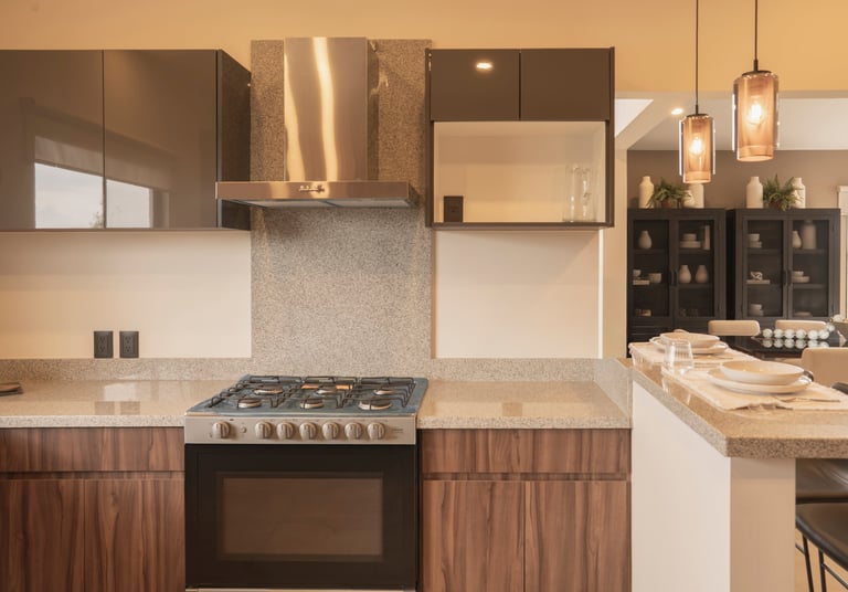 Modern kitchen with stainless steel range hood, gas cooktop, light granite countertops, and wood-grain cabinetry with glass upper cabinets.