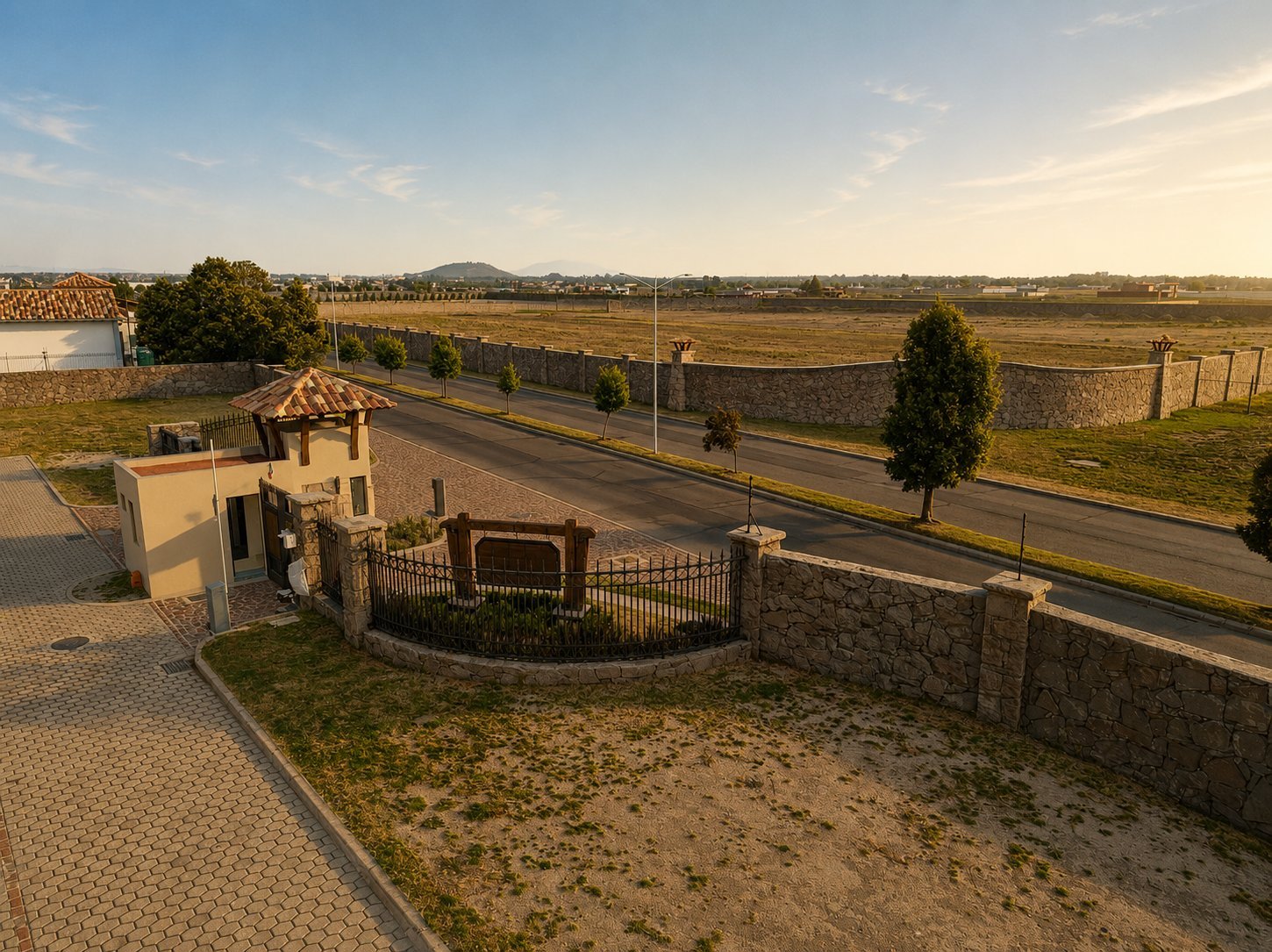 Aerial view of a stone house with terracotta roof beside a paved road in a rural agricultural landscape with fields and trees